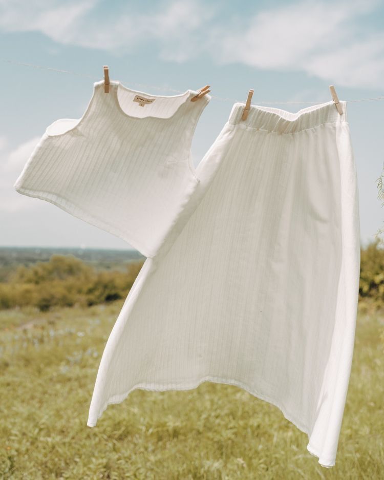 White top and skirt drying on a washing line above a green meadow